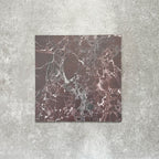 Close-up of Divine Levant Rouge matt marble-effect tile in a 30cm x 30cm format, featuring deep burgundy and rich red tones with intricate white and grey marble-inspired veining. The bold natural stone effect and dramatic colour variation create a luxurious statement finish, ideal for chequerboard floor designs, feature areas and characterful interior spaces.