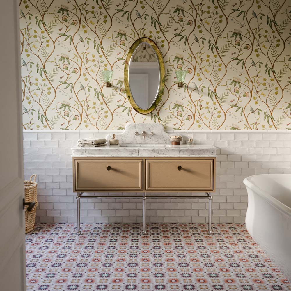 Bathroom featuring Dordogne White Blanca Rustic Gloss 7.5cm x 15cm wall tiles, paired with colourful patterned floor tiles, botanical wallpaper, a marble vanity, oval mirror and freestanding bath.
