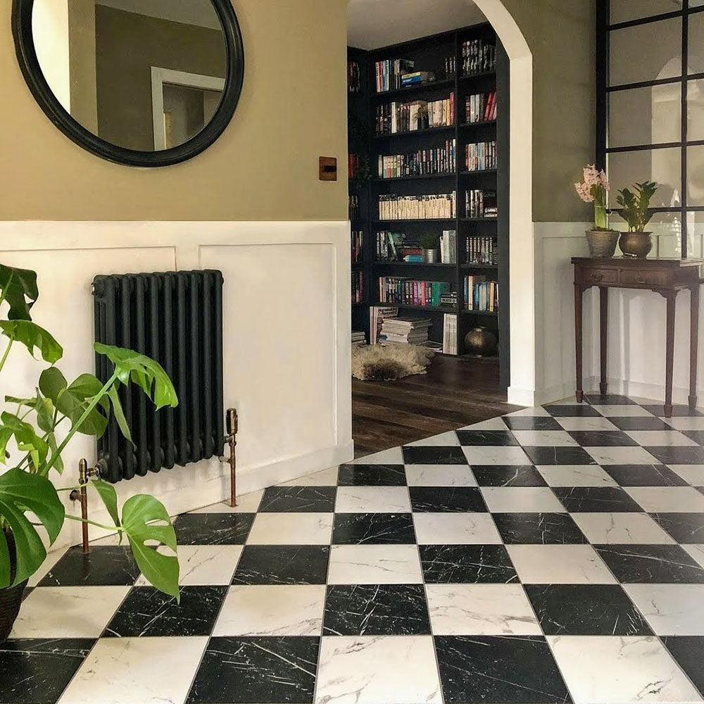 Entrance hallway featuring Florence Calacatta White 25x25cm marble-effect porcelain floor tiles, laid in a classic black and white checkerboard pattern and styled with period detailing, dark wood furniture and soft green walls for a timeless, elegant look.