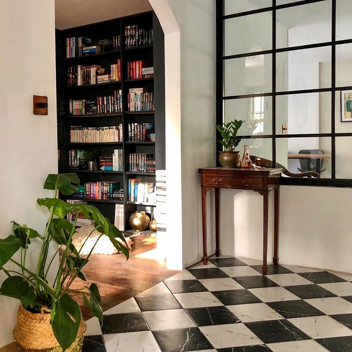 Entrance hallway featuring Florence Calacatta White 25x25cm marble-effect porcelain floor tiles, laid in a classic black and white checkerboard pattern and styled with period detailing, dark wood furniture and soft green walls for a timeless, elegant look.