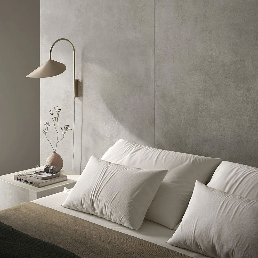Bedroom interior featuring Etna Grey Matt 60 × 60cm porcelain wall tiles, styled with soft neutral bedding, a minimalist bedside table, and warm lighting for a calm, contemporary, restful space.