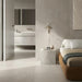 Bedroom interior featuring Etna Pearl Matt 60 × 60cm porcelain floor tiles, styled with soft neutral tones, a low upholstered bed, minimalist furniture, and a seamless transition into an adjoining bathroom space.