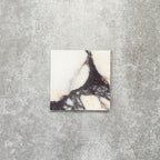 Fayrouz Calacatta Viola honed natural marble tile in a 15.2cm x 15.2cm square format, featuring a creamy white background with bold purple veining and subtle warm gold tones, creating a luxurious and timeless natural stone finish.