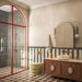 Contemporary bathroom featuring Fayrouz Latte Foam tumbled natural marble floor tiles in a classic chequerboard layout, paired with a walnut vanity, brushed brass fittings and a striking red-framed shower enclosure for a warm, timeless interior.