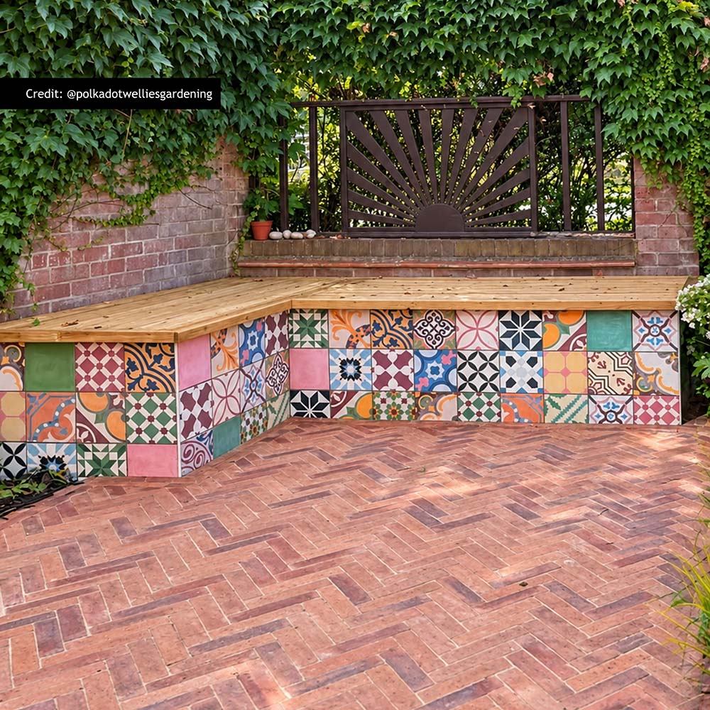 Fayrouz Patchwork 20cm x 20cm Moroccan style tiles, bringing an eclectic mix of colour and pattern to this outdoor seating area, paired with warm herringbone paving and natural greenery.