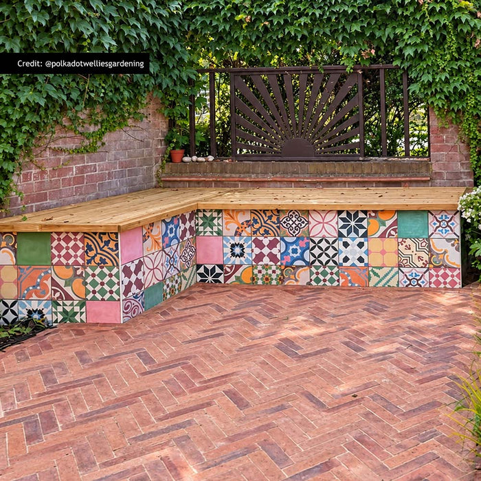 Fayrouz Patchwork 20cm x 20cm Moroccan style tiles, bringing an eclectic mix of colour and pattern to this outdoor seating area, paired with warm herringbone paving and natural greenery.