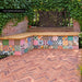 Fayrouz Patchwork 20cm x 20cm Moroccan style tiles, bringing an eclectic mix of colour and pattern to this outdoor seating area, paired with warm herringbone paving and natural greenery.