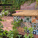 Fayrouz Patchwork 20cm x 20cm Moroccan style tiles, bringing an eclectic mix of colour and pattern to this outdoor seating area, paired with warm herringbone paving and natural greenery.