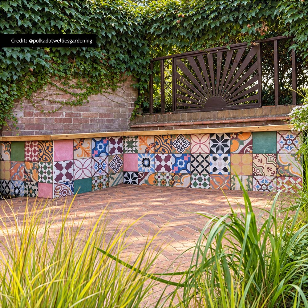 Fayrouz Patchwork 20cm x 20cm Moroccan style tiles, bringing an eclectic mix of colour and pattern to this outdoor seating area, paired with warm herringbone paving and natural greenery.