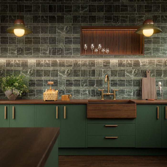 Kitchen featuring Fayrouz Verde Honed Finish Natural Marble 5cm x 20cm splashback tiles, laid in a brick pattern and paired with deep green cabinetry, dark wooden worktops, brass fittings and warm ambient lighting.