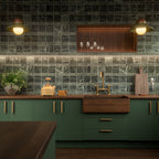 Kitchen featuring Fayrouz Verde Tumbled Finish Natural Marble 15.2cm x 15.2cm splashback tiles, paired with deep green cabinetry, dark wooden worktops, brass fittings, open shelving and warm ambient lighting for a timeless design.
