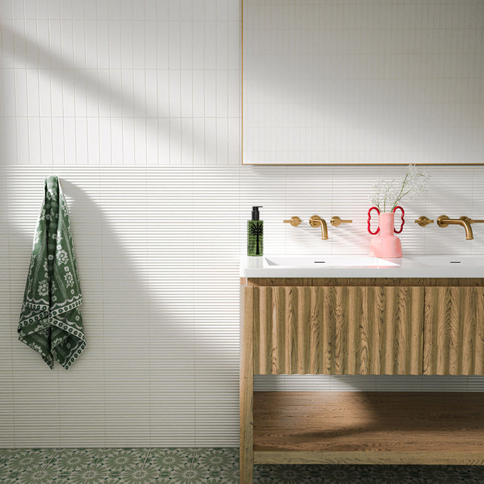 Fez Jade Green 20cm x 20cm Moroccan style patterned tiles, featuring a repeating floral design in soft green and white across the bathroom floor, paired with glossy white wall tiles, natural wood and warm brass details.