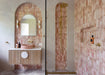 Contemporary bathroom featuring Foundry Coral Pink 6.5cm x 20cm wall tiles, laid vertically across arched vanity and shower areas, paired with brass fittings, a wooden vanity and herringbone flooring.