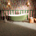Bathroom featuring Foundry Coral Pink 6.5x20cm gloss wall tiles, arranged vertically alongside jade green tiles, paired with colourful floral wallpaper, a freestanding sage green bathtub, brass fixtures and terrazzo effect floor tiles.