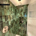 Walk-in shower featuring Foundry Bricks Jade Green Wall Tiles 6.5cm x 20cm, laid vertically with striking shade variation, paired with brushed stainless steel shower fittings, a recessed storage niche and a fluted glass shower screen.