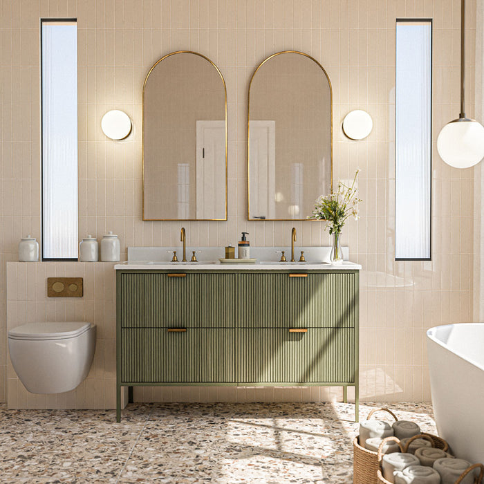 Bathroom featuring Gallery Beige Gloss 5cm x 20cm wall tiles, laid vertically in a soft neutral tone and paired with terrazzo-style floor tiles, a fluted green vanity, brass details and arched mirrors.