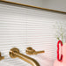Gallery Decor White Gloss 5cm x 20cm 3D fluted wall tiles, featuring a glossy white finish with raised linear texture, paired with warm brass fittings and soft pink accents.