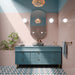 Gallery Stony Pink Gloss 5cm x 20cm brick wall tiles, featuring a soft blush pink finish across the bathroom walls, paired with a teal vanity, patterned floor tiles and warm brass details.