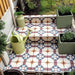 Garden steps featuring London Streets Berlin Street 20x20cm Victorian Moroccan style floor tiles, styled with potted plants and a watering can, showcasing a decorative patterned outdoor tile design in soft blue, burgundy and cream tones.