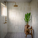 Bathroom featuring Gilgamesh Vintage White Moroccan style floor tiles, combining a classic black and white geometric pattern with decorative star motifs for a timeless statement underfoot. Paired with soft white wall tiles, warm brass shower fittings and natural wood accents, the design balances traditional character with a bright, contemporary feel, making the space both elegant and inviting.
