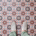 Fez Rosso Moroccan-style porcelain tiles laid in a neat grid, creating a rich, rhythmic pattern across the floor. Warm terracotta red starbursts sit against a soft grey-blue base, balanced by delicate blush pink and white geometric details inspired by traditional Moroccan tilework. Styled here with neutral footwear for scale, the design feels bold yet refined—perfect for adding warmth and character to kitchens, hallways or statement floor spaces while remaining practical and durable in porcelain.