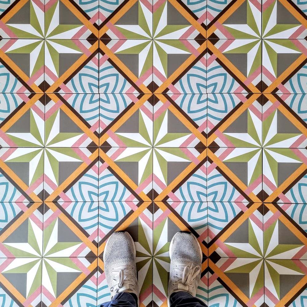 Cuba Star Moroccan-style porcelain tiles in a 20×20cm square format, arranged in a repeating geometric star pattern in soft green, blue, pink and mustard tones, shown from above to highlight the tile’s bold symmetry, crisp lines and decorative encaustic-style design.