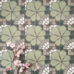 Nantes Green Moroccan-style patterned tiles in a 20x20cm format, arranged in a repeating grid to showcase the full design. The soft green floral motif is paired with mosaic-effect detailing in muted greys, creams and white, styled with delicate pink blossom accents to highlight the decorative, vintage-inspired pattern.