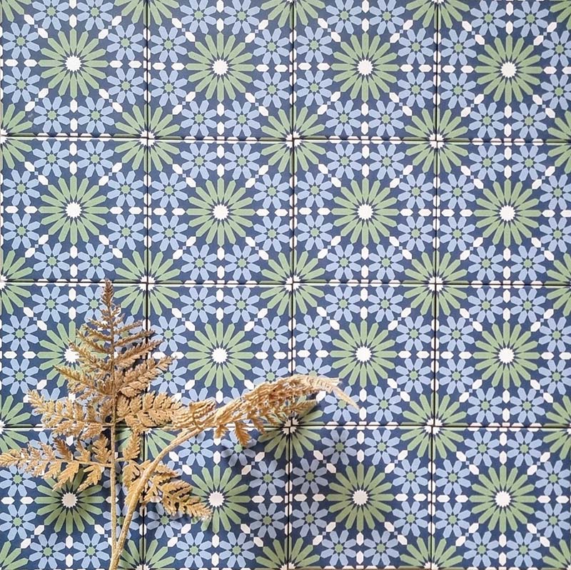 Fez Mini Springs 15x15cm Moroccan-style porcelain wall tiles arranged in a repeating geometric pattern, featuring layered blue and soft green star motifs, styled with dried foliage for a natural, decorative finish.