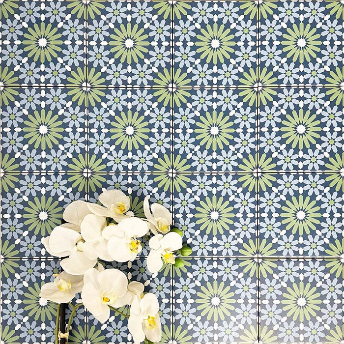 Fez Mini Springs 15x15cm Moroccan-style porcelain wall tiles arranged in a repeating geometric pattern, featuring layered blue and soft green star motifs, styled with white orchid flowers for a fresh, decorative finish.