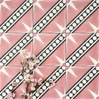 Gilgamesh Pink Moroccan style 20x20cm patterned tiles, shown in a flat lay with decorative foliage to highlight the geometric star design in soft pink, black and white.
