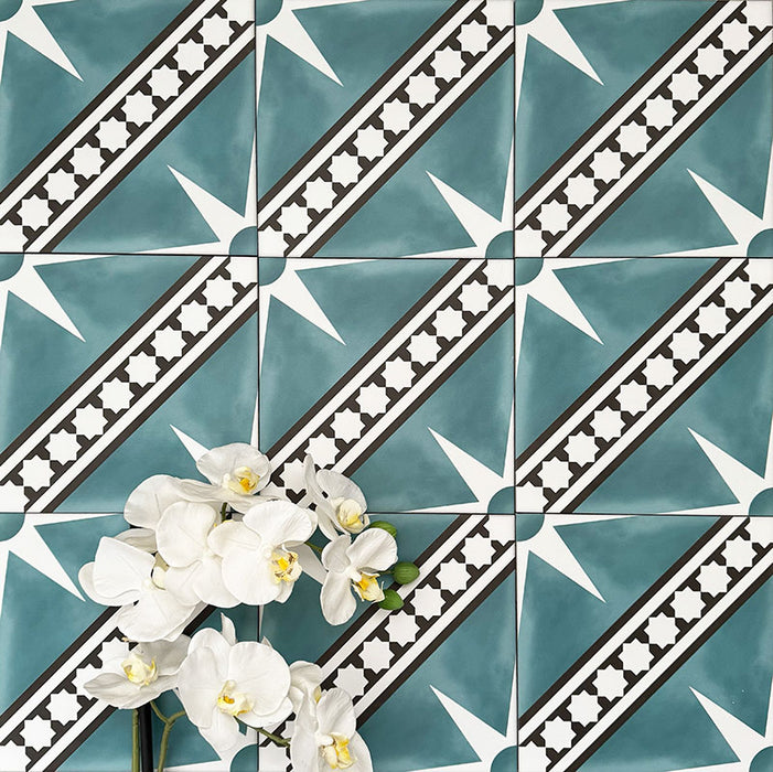 Gilgamesh Blue Moroccan style 20x20cm patterned tiles, shown in a flat lay with decorative foliage highlighting the blue, black and white geometric star design.