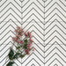 Almeria Jilani White Moroccan-style porcelain wall and floor tiles arranged in a repeating black line chevron pattern on a white base, 20x20cm, styled with decorative flowers.