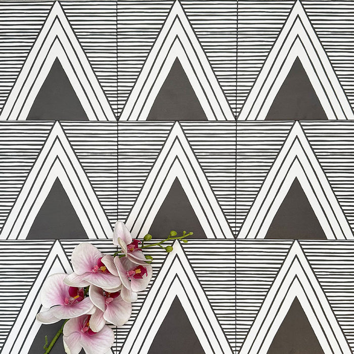 Almeria Giza Moroccan-style porcelain wall and floor tiles arranged in a repeating black and white geometric triangle pattern, 20x20cm, styled with decorative flowers for a striking display.