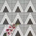 Almeria Giza Moroccan-style porcelain wall and floor tiles arranged in a repeating black and white geometric triangle pattern, 20x20cm, styled with decorative flowers for a striking display.