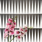 Almeria Backgammon Moroccan-style porcelain wall and floor tiles arranged in a bold black and white geometric pattern, 20x20cm, styled with decorative flowers for a striking display.
