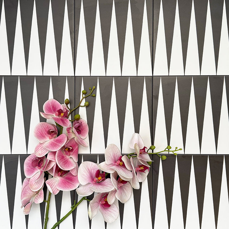 Almeria Backgammon Moroccan-style porcelain wall and floor tiles arranged in a bold black and white geometric pattern, 20x20cm, styled with decorative flowers for a striking display.