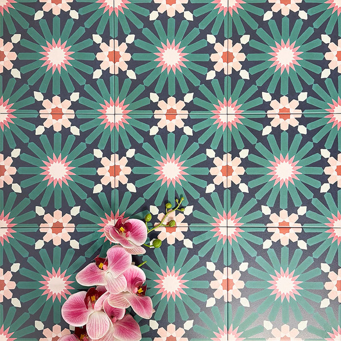 Fez Festival 20x20cm Moroccan-style porcelain wall tiles arranged in a repeating geometric pattern, featuring bold teal, pink and warm neutral star motifs, styled with pink orchid flowers for a vibrant, decorative finish.