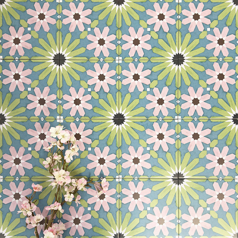 Fez Summer 20x20cm Moroccan-style porcelain wall tiles arranged in a repeating geometric pattern, featuring soft green, blue and blush pink star motifs, styled with delicate floral stems for a fresh, decorative finish.