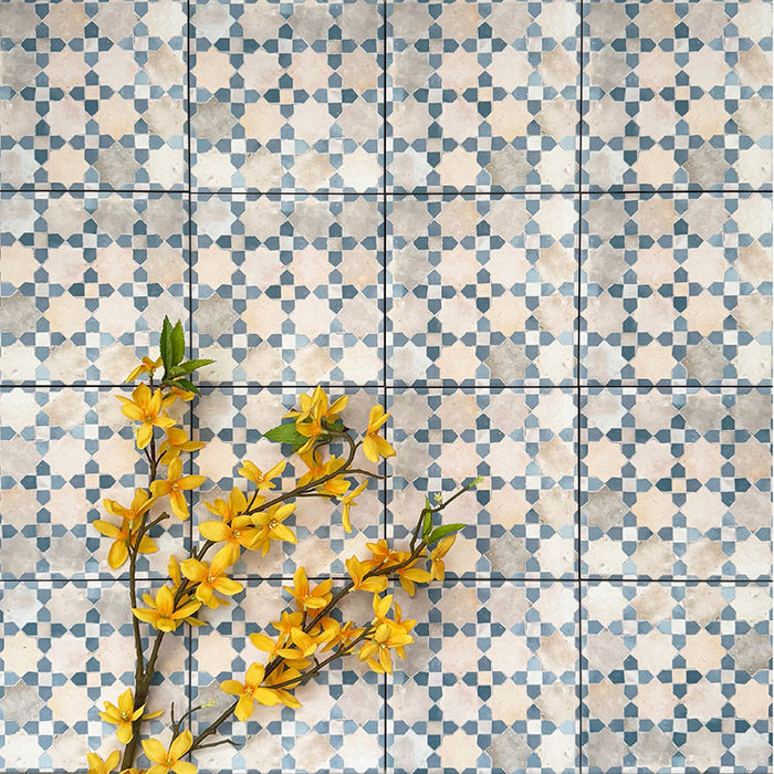 Berber Mequinez Blue 15×15cm Moroccan-style porcelain tiles laid in a grid pattern, showcasing a soft blue and cream geometric design with decorative floral styling.