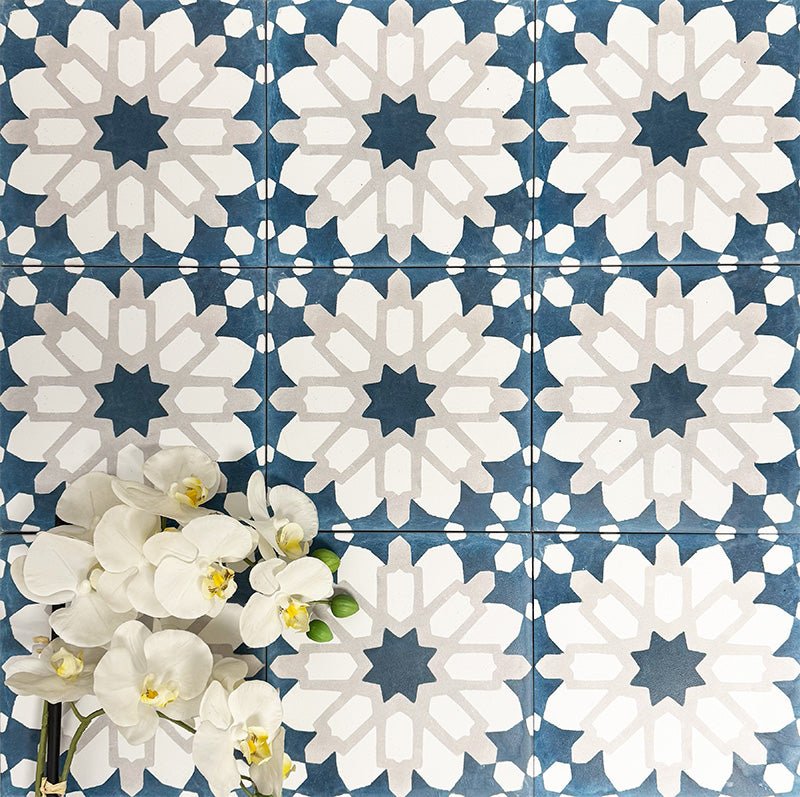Souk Blue D 20×20cm Moroccan-style porcelain tiles arranged in a blue, white and grey geometric pattern.