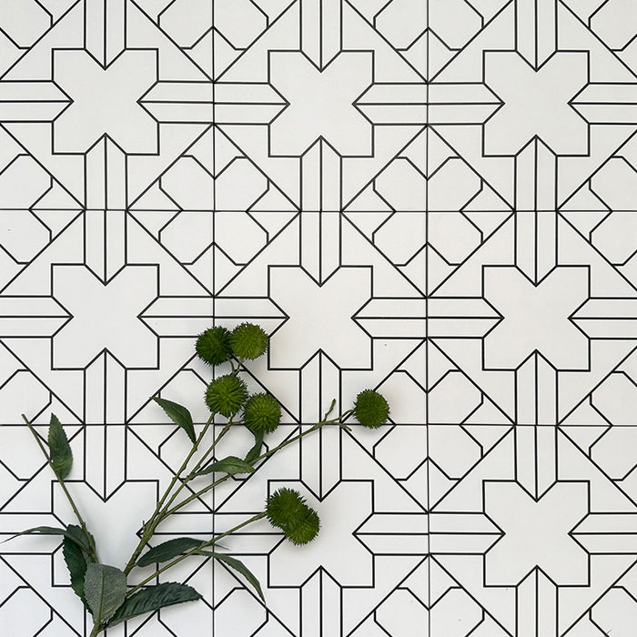 Almeria Palace Moroccan-style porcelain wall and floor tiles arranged in a repeating black line geometric pattern on a white base, 20x20cm, styled with greenery for a decorative display.