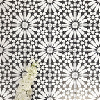 Fez Winter Moroccan-style porcelain tiles laid in a repeating pattern, showcasing a striking black and white geometric star design. The 20 × 20cm tiles create a bold, high-contrast encaustic-effect surface, styled with white florals to highlight the crisp detailing and symmetry. Ideal for statement floors, feature walls, splashbacks, and contemporary or monochrome interior schemes.