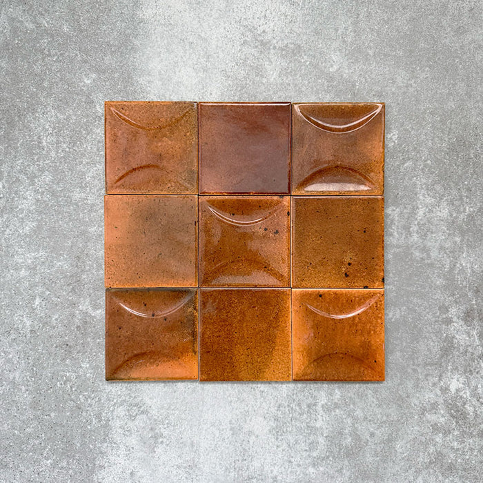 Close-up of Saigon Amber Decor Square Wall tiles, featuring Moroccan-style 10 × 10cm glossy ceramic tiles in warm amber tones with a curved decorative relief pattern.