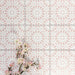 Fez Rose Pink Moroccan-style porcelain tiles laid in a repeating grid, creating a soft, decorative pattern across the surface. The blush pink background is paired with a crisp white geometric starburst motif, forming a delicate yet eye-catching design inspired by traditional Moroccan tiles. Styled with pale pink blossom branches in the corner, the overall look feels light, elegant and feminine—perfect for adding subtle pattern and warmth to bathrooms, kitchens or feature walls.
