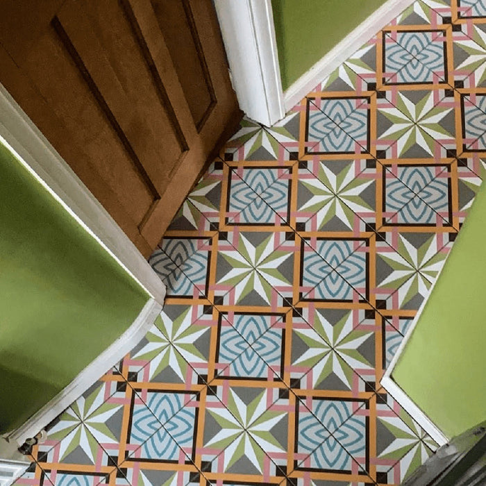 Hallway floor featuring Cuba Star Moroccan-style porcelain tiles in a 20×20cm square format, laid in a repeating geometric pattern with soft green, blue, pink and mustard tones, paired with green walls and wooden doors to create a vibrant, characterful entrance.