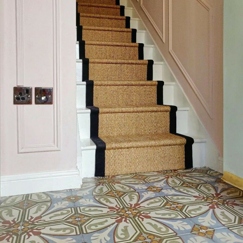 Victorian-style hallway featuring Viscount Langholme Place 20×20cm porcelain wall and floor tiles laid in a repeating floral and geometric pattern in soft blue, sage green, warm red and cream tones, styled alongside a classic staircase with natural sisal runner, white panelling and traditional detailing.