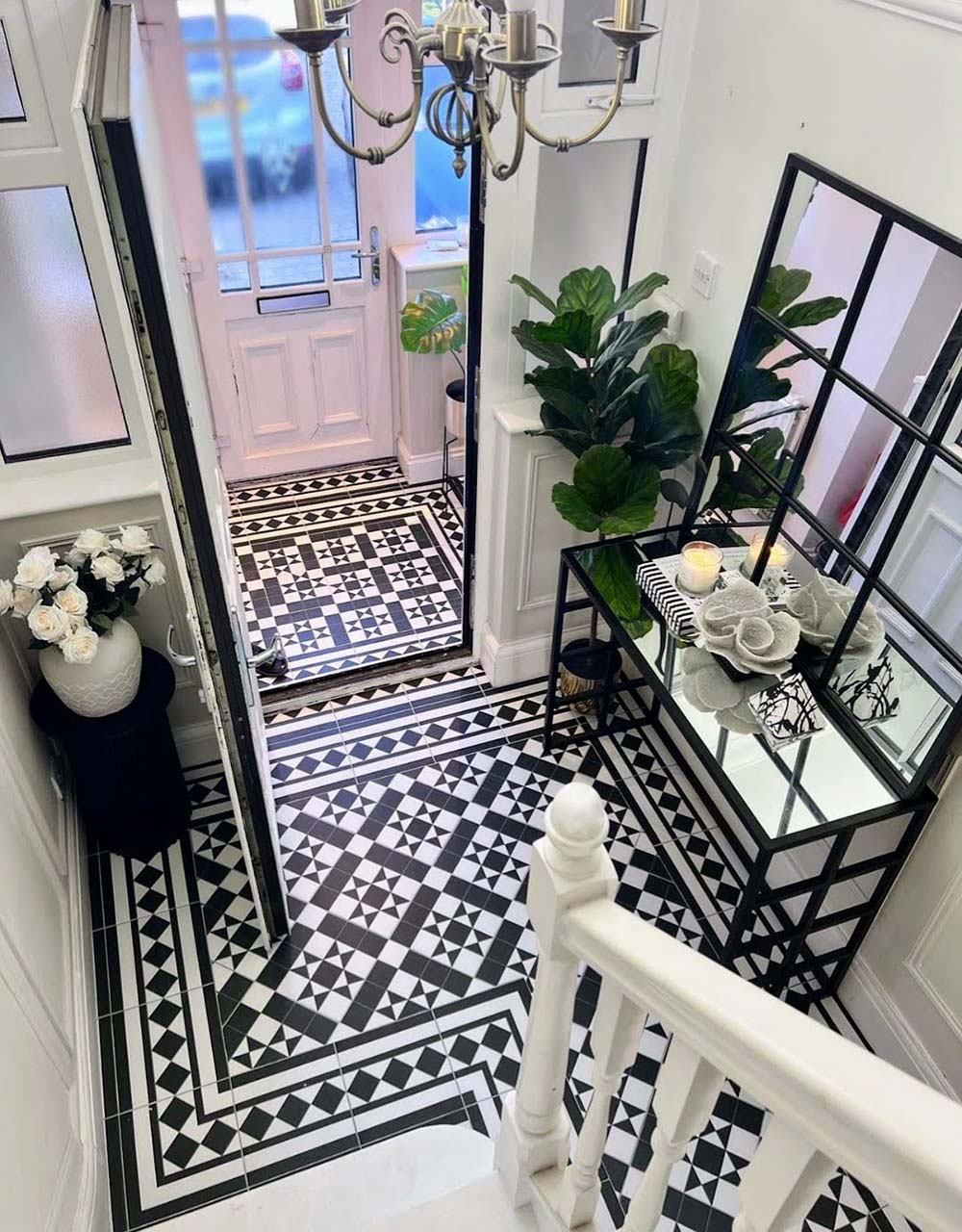 Hallway featuring Dorset Tile Black & White Victorian-style porcelain floor tiles in a 25 × 25cm format, laid in a striking geometric pattern with a decorative border, paired with a classic staircase, black wood panelling and traditional period details.