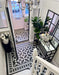 Hallway featuring Dorset Tile Black & White Victorian-style porcelain floor tiles in a 25 × 25cm format, laid in a striking geometric pattern with a decorative border, paired with a classic staircase, black wood panelling and traditional period details.