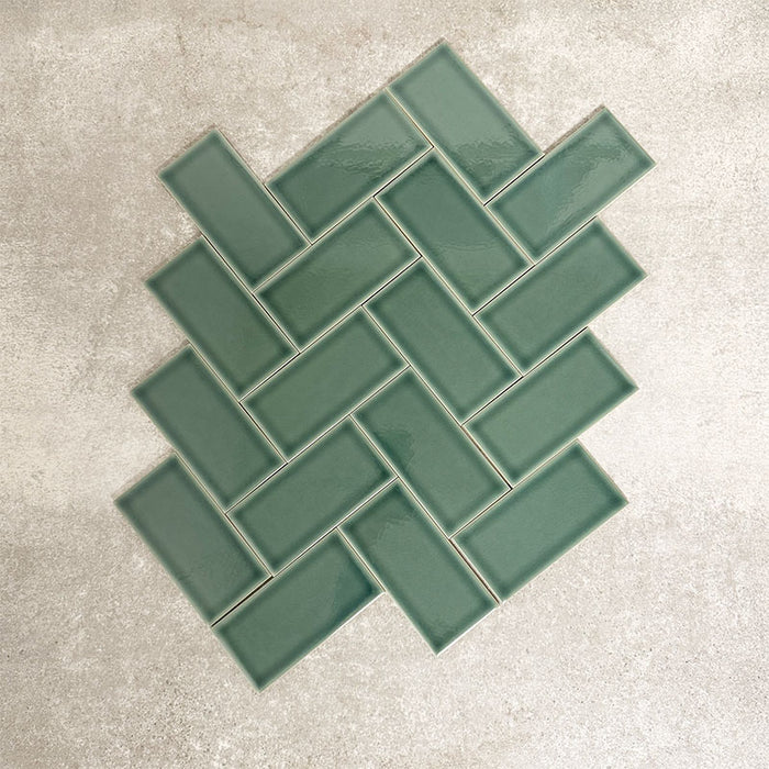 Pimlico Golders Green 7.5 × 15cm ceramic wall tiles with a crackle glaze finish, shown in a herringbone layout highlighting rich green tones, subtle texture and versatile design for kitchens and bathrooms.