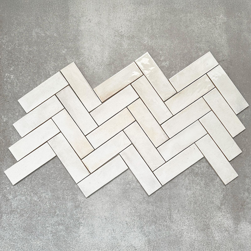 Saigon White Brick Wall tiles laid in a herringbone pattern, showcasing Moroccan-style 5.1 × 16.1cm glossy ceramic tiles in soft white tones with subtle tonal variation.